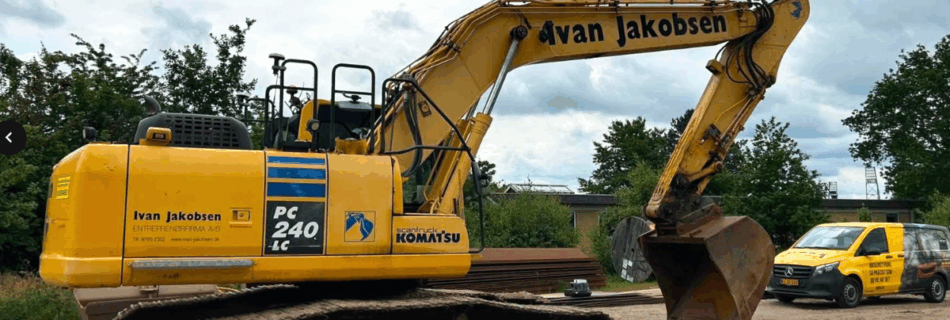 Large yellow excavator with 'Ivan Jakobsen' branding on a construction site, ready to dig, with a yellow van in the background on dirt ground
